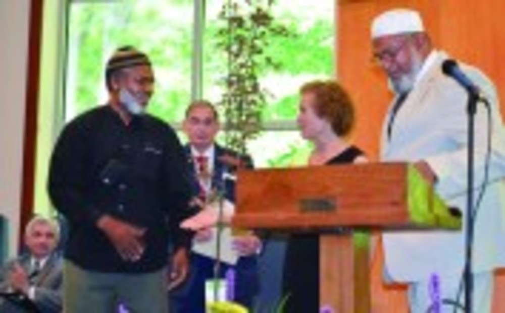 Torat Yisrael President Susan Smoller accepts a tree – a gift from the local Muslim community – from Imam Walid Muhammad, as Andrew Sholes, center and Imam Farid Ansari observe.  /NANCY KIRSCH